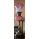 A Victorian double burner oil lamp with moulded opaque pink glass reservoir on brass column stand