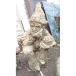 A concrete garden statue depicting a thinking gnome