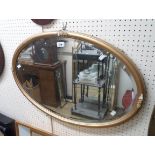 An early 20th Century gilt framed bevelled oval wall mirror - some loss to applied floral