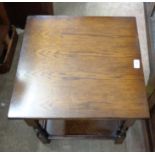 A 20th Century oak effect two tier tea table with turned supports