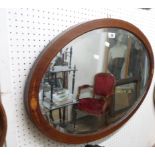 An Edwardian inlaid mahogany framed bevelled oval wall mirror