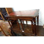 A reproduction mahogany coffee table with red leather inset top and flanking nesting tea tables