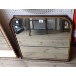 A 20th Century mahogany and parcel gilt framed bevelled wall mirror with shaped top corners