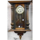 An early 20th Century stained wood cased Vienna style wall clock with visible pendulum and spring