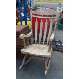 A wooden lathe back elbow rocking chair with carved decoration set on turned supports