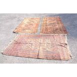 Three early 20th Century handmade Middle Eastern rugs with repeat motifs on hot orange, brown and