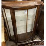 An 89cm vintage stained mixed wood bow front display cabinet with material lined interior and
