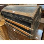 A small Victorian dome-top travelling trunk with weather coating and flanking iron drop handles -