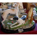 A resin dog figurine depicting three greyhounds on a wooden plinth