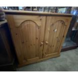 An 80cm modern pine cupboard enclosed by a pair of panelled doors, set on bracket base