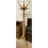 A polished blonde wood freestanding hat and coat stand with turned decoration, set on tripod