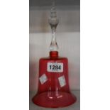 A Victorian cranberry glass bell with applied clear glass handle and original clapper