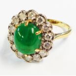 A hallmarked 18ct. gold ring, set with central emerald cabochon within a fourteen stone diamond