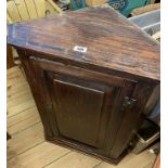 A 57cm antique oak wall hanging corner cabinet with canted sides and panelled door