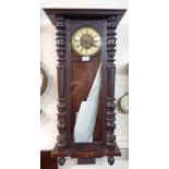 An early 20th Century stained wood cased Vienna regulator style wall clock with visible pendulum and