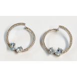 A pair of marked 18k/750 cross-over hoop hinged ear-rings, each set with two aquamarines and diamond