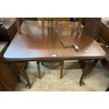 An early 20th Century stained walnut extending dining table with leaf and winder, set on cabriole