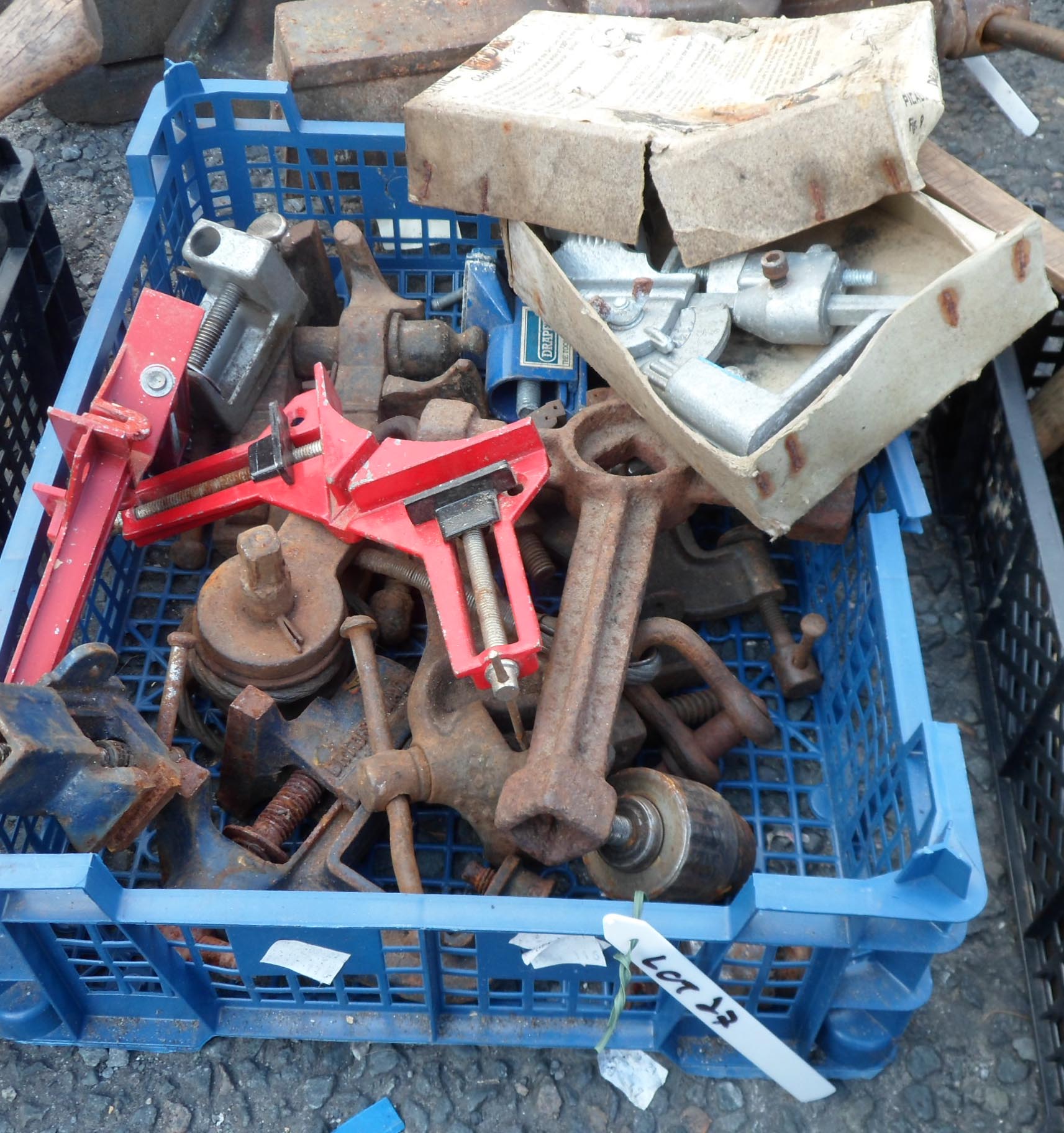 A crate of assorted tools including drill grinding jig, clamps, small vices, etc.