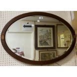 An Edwardian inlaid mahogany framed bevelled oval wall mirror