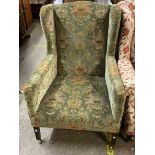 An early 20th Century box framed wing-back armchair upholstered in floral tapestry, set on square