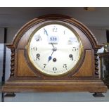 A vintage oak cased break dome top mantle clock with flanking barley twist decoration and eight