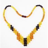 An Art Deco style coloured amber bead necklace with shaped pendant end