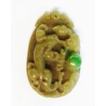 An Oriental carved bi-colour jadeite pendant with stylised dragon and pearl decoration