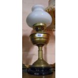 An old brass oil lamp with chimney and opaque glass shade