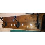 A vintage stained wood and iron wall mounted three hook coat rack with inset 6d coin