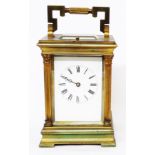 An old brass and bevelled glass cased carriage clock with Corinthian columns to corners and strike