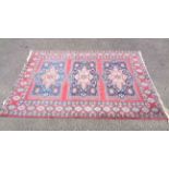 A 20th Century handmade sanforized wool on cotton rug with three central medallions on red ground