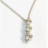 A high carat white metal three stone diamond pendant, on import marked 750 white gold chain