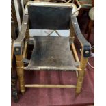A vintage stained wood framed elbow chair with slung leather upholstery, set on bobbin turned