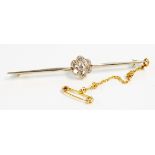 An unmarked yellow metal bar brooch with diamond encrusted flowerhead pattern setting, with safety