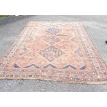 An early 20th Century Iranian handmade rug with three central hook bordered motifs on russet