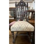 An antique ornate carved oak framed standard chair with later upholstery to seat, set on turned