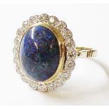 A marked 18ct ring, set with central large black opal cabochon within a diamond encrusted border -