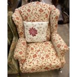 A modern wing back armchair in the antique style with floral tapestry upholstery, set on turned