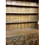 A 1.35m antique waxed pine two part dresser with three shelf open plate rack over a base with two