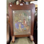 A 1930's mixed wood fire screen with embroidered panel under glass, set on Art Deco feet