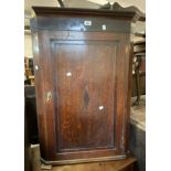 A 64cm late Georgian oak and mahogany strung wall mounted corner cabinet enclosed by a panelled