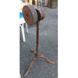 An old knife grinding wheel set on a cast iron pedestal tripod base with gear system and crank
