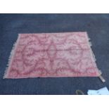 A small machine made rug with floral design on pink ground