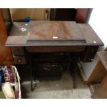 An old Singer treadle sewing machine with drawers to top containing a quantity of sewing