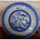 A Japanese blue and white porcelain dish decorated with a variation of the Willow pattern