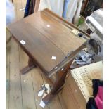 An old stained oak school desk with bi-folding slope top, set on shaped standard ends a/f