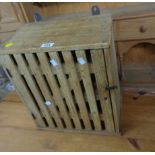 A small old pine wall mounted cabinet with adapted spice jar interior enclosed by a rustic door