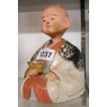 An early 20th Century Japanese pottery nodding head figurine depicting a seated man in glazed and