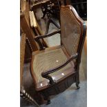 An old mahogany framed commode elbow chair with rattan back and seat panels, set on cabriole legs