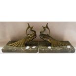 A pair of Art Deco cast brass peacock form bookends on marble plinths